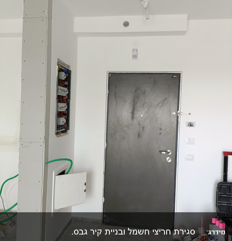 עמוד גבס עם לוח חשמל פתוח וחוטים ירוקים